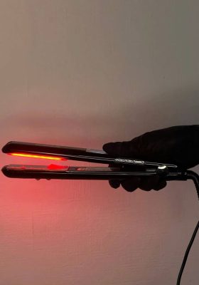 Використання професійної праски з червоним світлом для глибокого живлення волосся під час холодного відновлення в салоні краси.